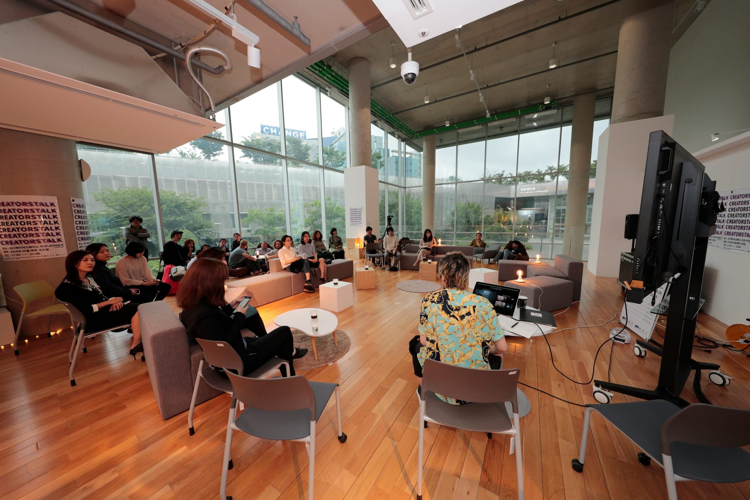 People sitting and talking around low tables in a bright, glass-walled event space