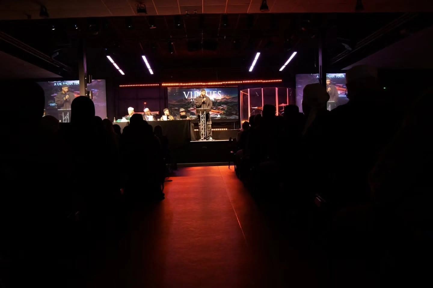 An audience seated at a live event, facing a lit stage