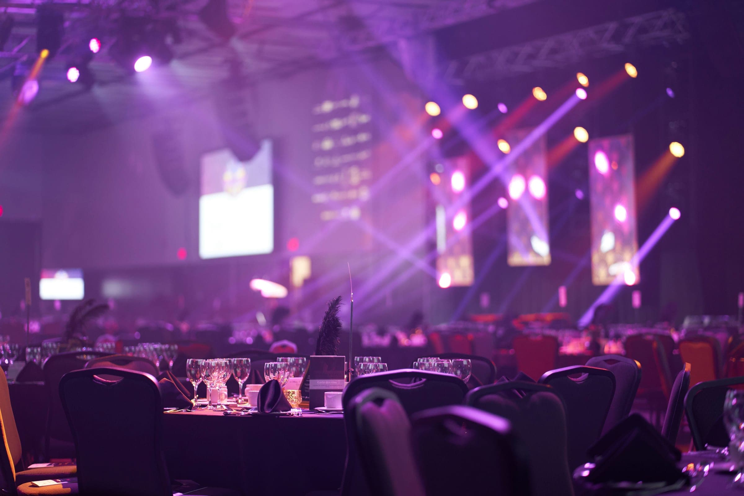 A formal gala dinner under purple stage lighting, tables set for guests