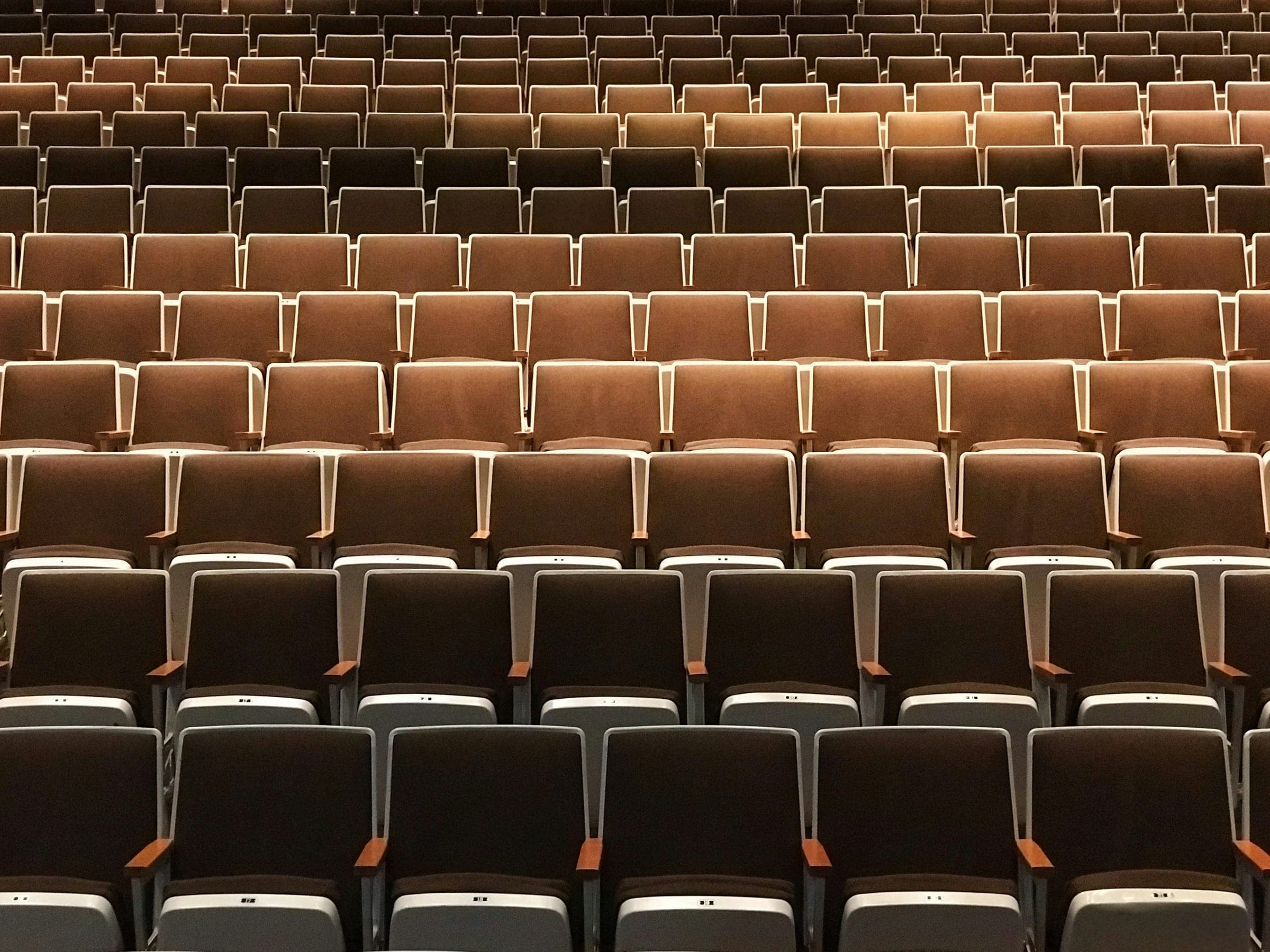 Rows of empty theatre seats under warm house lights before an audience arrives