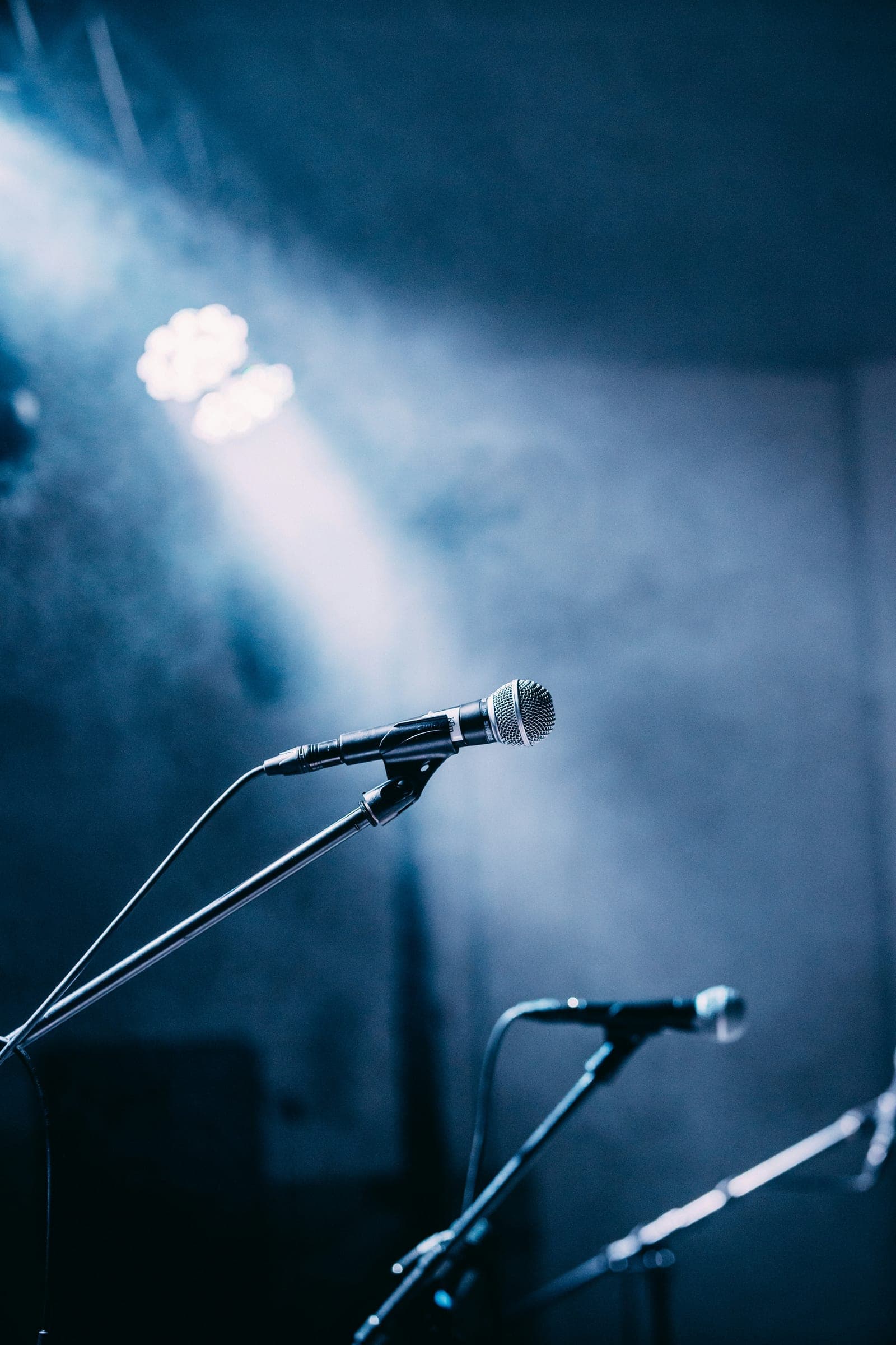 A microphone stand lit by a single stage spotlight